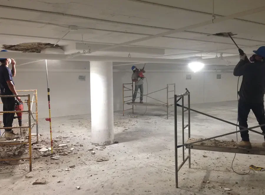 ICC workers using power tools to remove loose ceiling concrete in parking garage